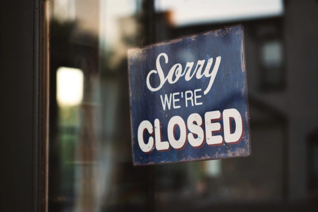Sorry We're Closed sign hanging on glass door