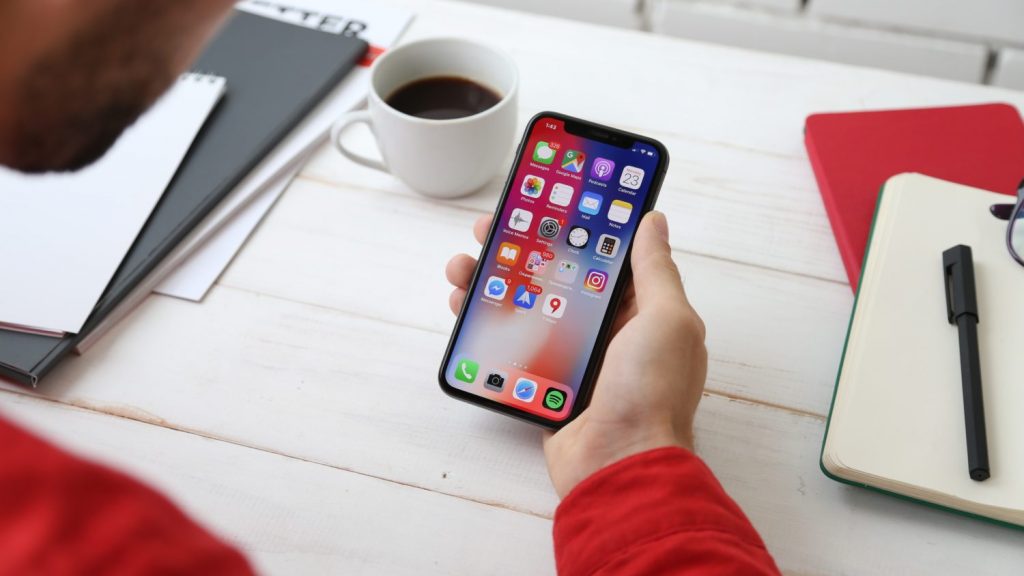 Man holding iPhone X at desk