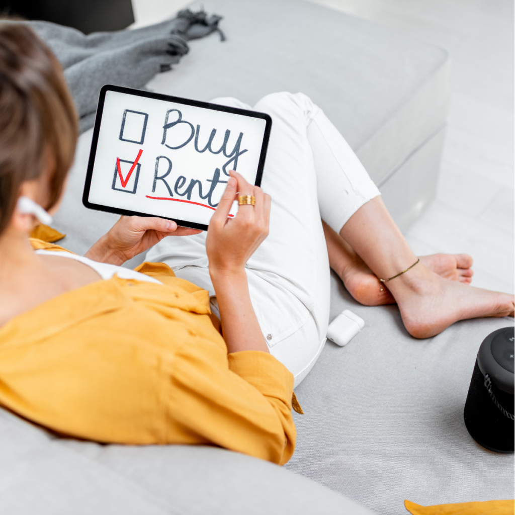 An overhead, top-down view looking down at a woman relaxing on a large, comfortable grey sofa under a patterned blanket. She is holding up a white tablet screen that clearly reads "BUY" and "RENT" in large, bold black letters, each preceded by an empty checkbox. On a surface to her left sits a warm coffee mug in a brightly lit, modern living room setting.